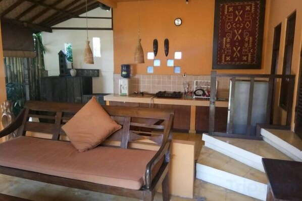 A room with a sofa, a kitchen area, and a staircase. - Gusde House and Villa Bali (Bali)