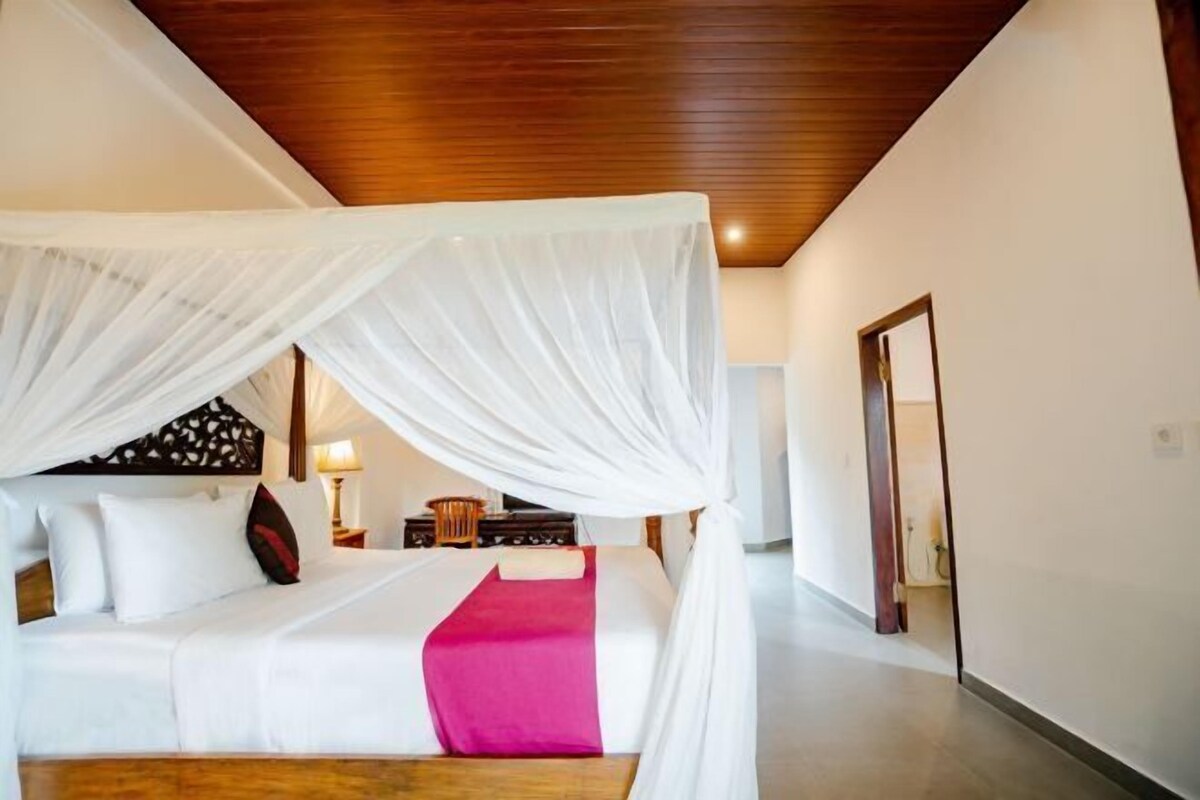 Um quarto com cama de dossel, mesa de cabeceira e criado-mudo.