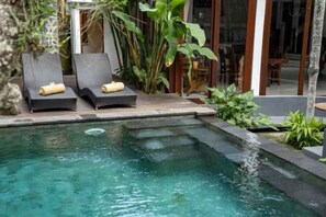 A pool area with two lounge chairs and a small waterfall feature. - Gusde House and Villa Bali (Bali)