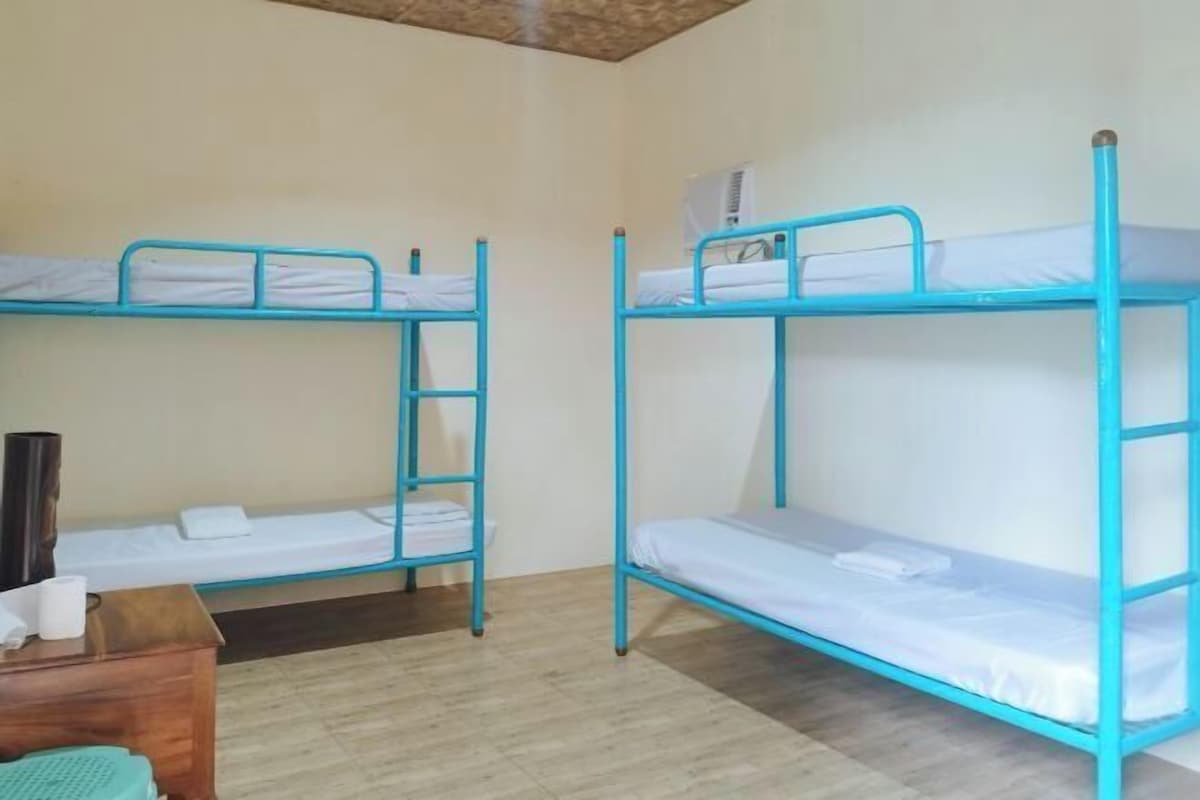 Una habitación con dos literas, un escritorio de madera y una mesita pequeña.