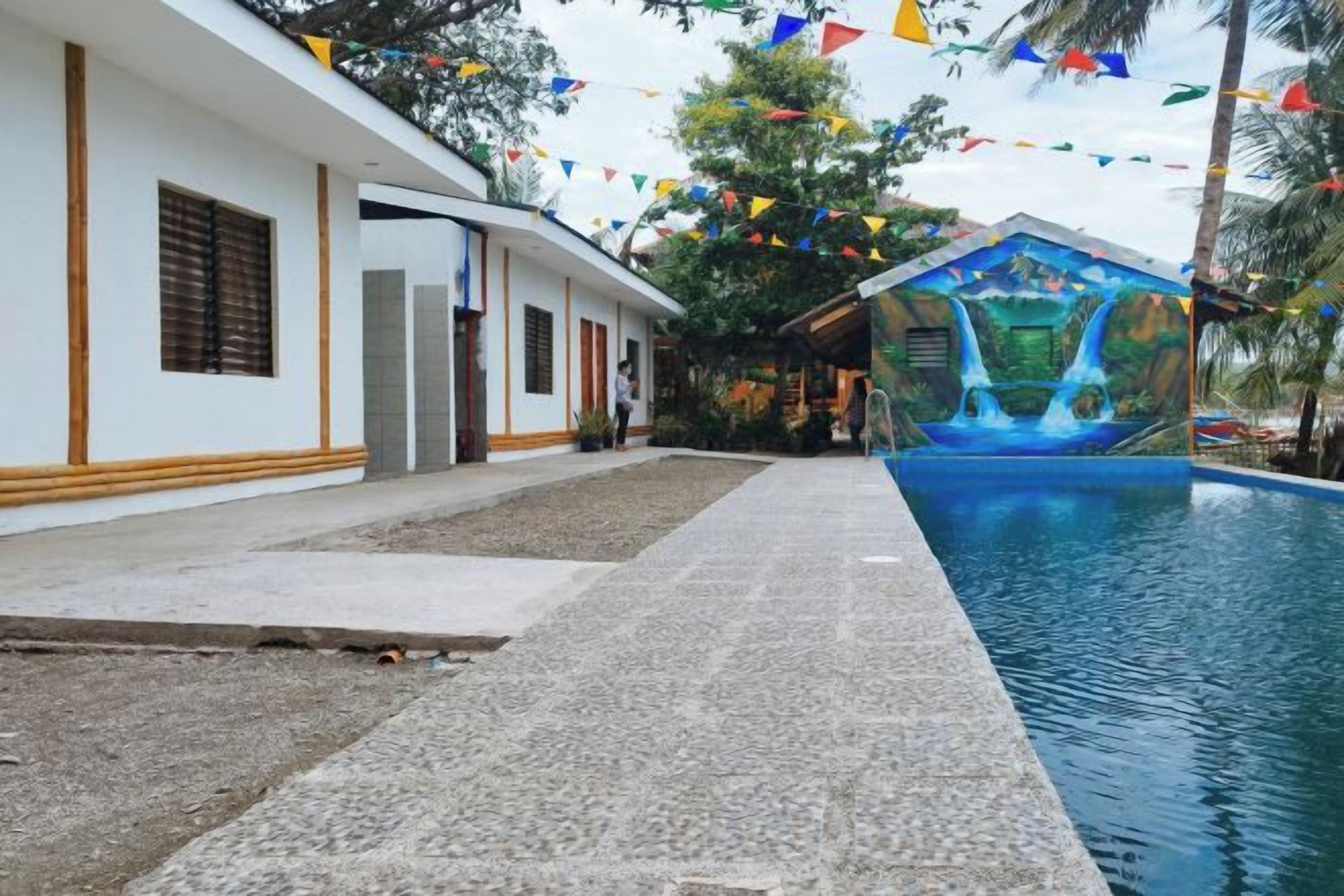 A swimming pool area with a building on one side and a mural on the other.