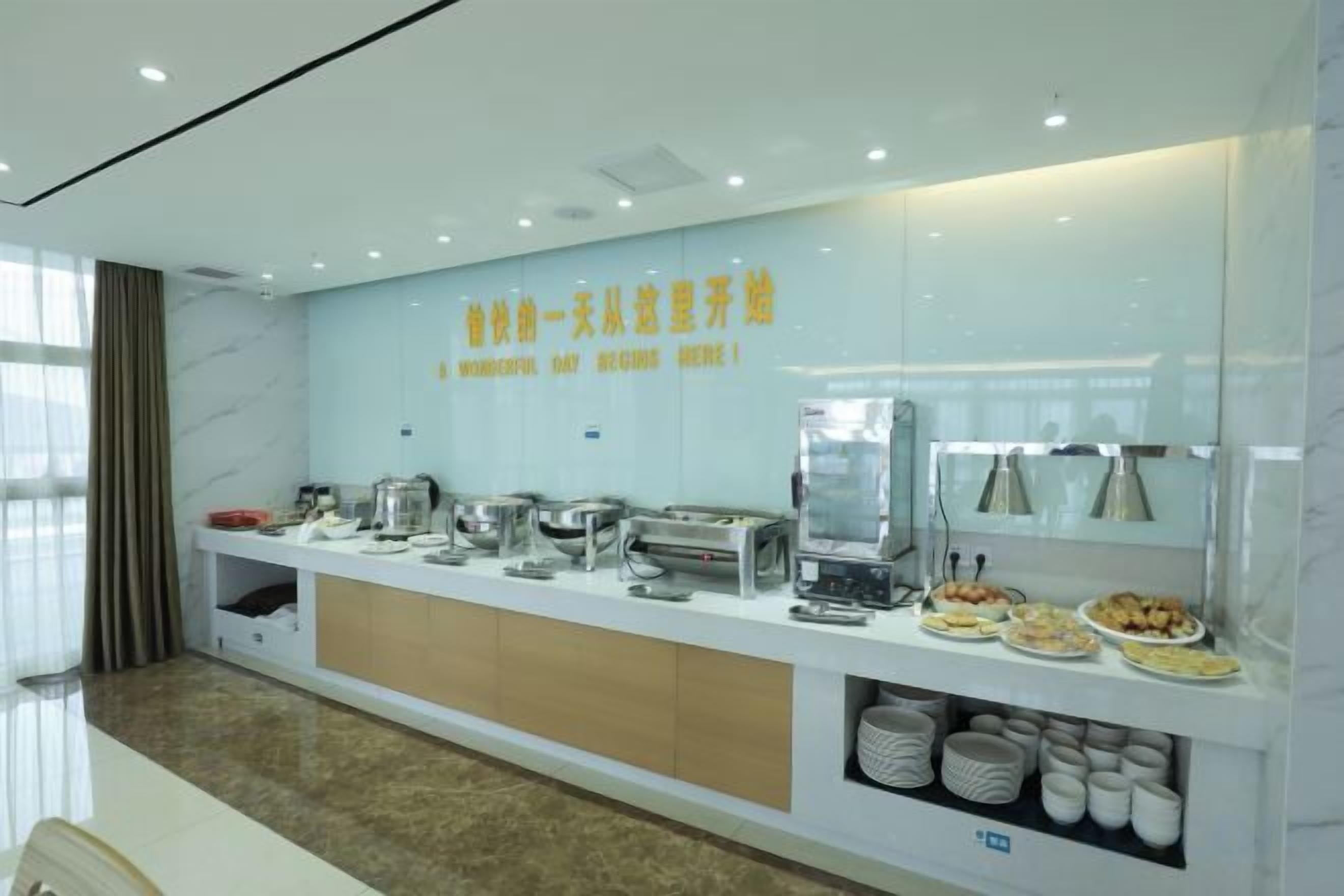 Eine moderne Hotelrezeption mit einer langen Theke, auf der verschiedene Speisen angeboten werden, und einem großen Spiegel darüber.