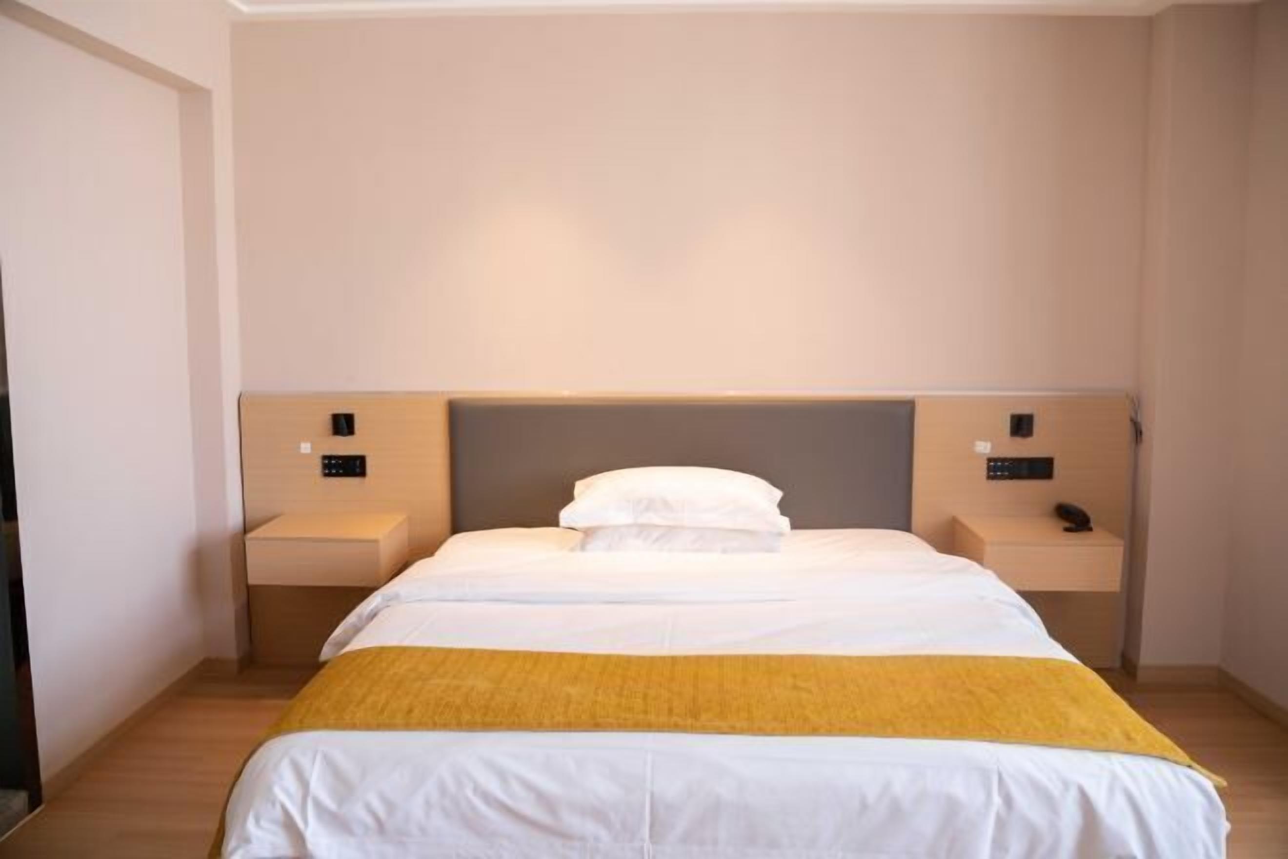 A hotel room with a large bed, two bedside tables, and a headboard.