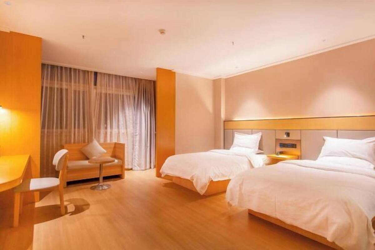 Une chambre d’hôtel avec deux lits, un canapé, une petite table et une chaise.
