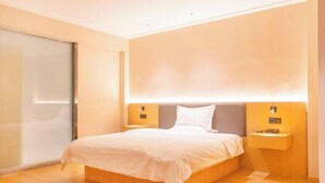 Une chambre d’hôtel moderne dotée d’un grand lit, d’un plancher en bois et d’un éclairage mural.