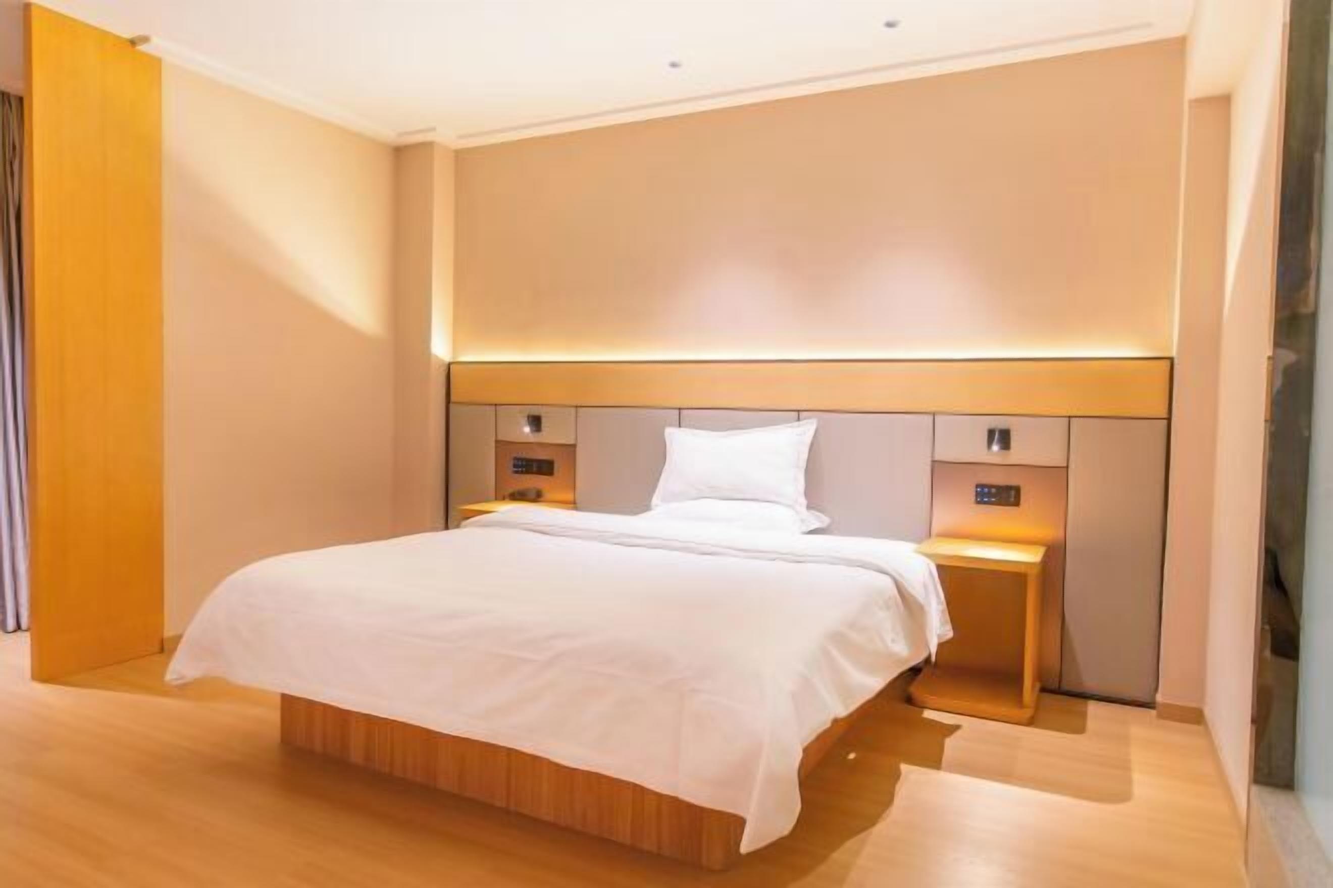 Una habitació d'hotel moderna amb un llit gran, taules de nit i un capçal amb il·luminació integrada.