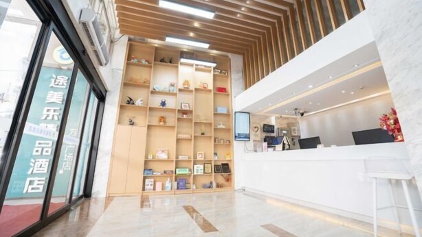 Un espace d’accueil d’hôtel au design moderne, comprenant un comptoir d’accueil en bois et un ordinateur fixé au mur.