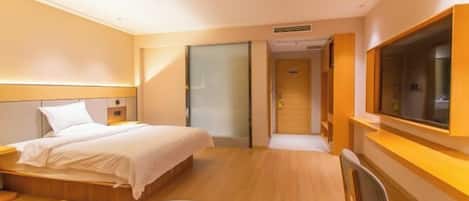 A hotel room with a bed, a desk, a chair, a TV, and a door leading to another room.