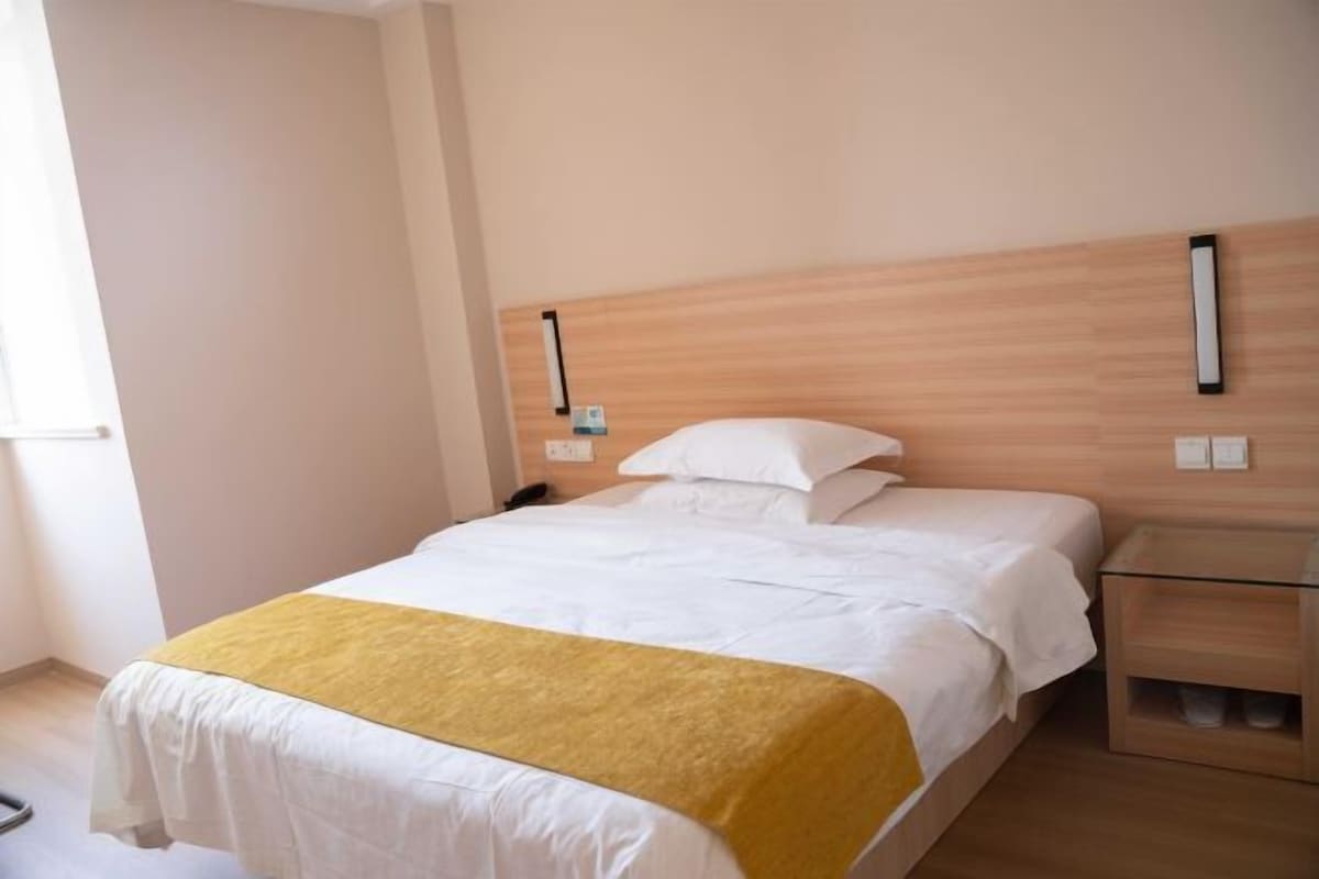 A hotel room with a bed, bedside table, and a nightstand.