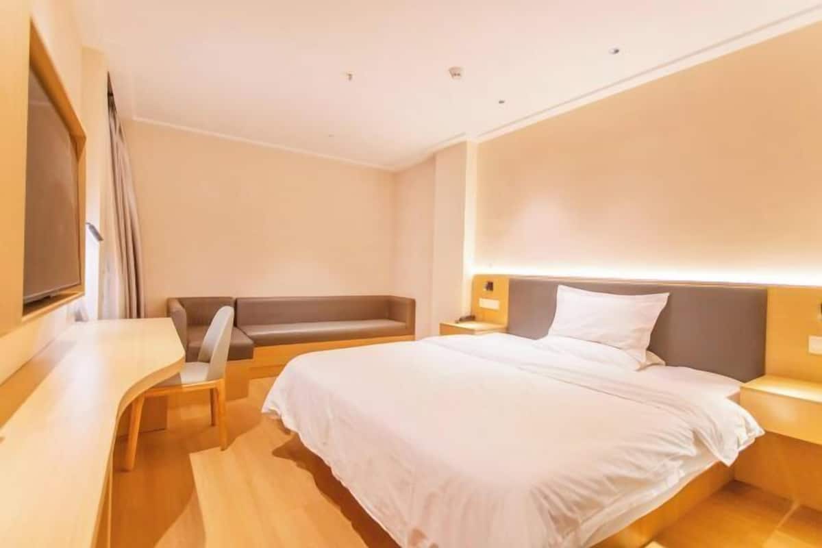 Une chambre d’hôtel avec un lit, un canapé, une télévision et un bureau.