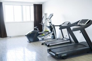 A gym with treadmills and elliptical machines, large windows, and a wooden floor. - Tumeile Boutique Hotel (Yangzhou)