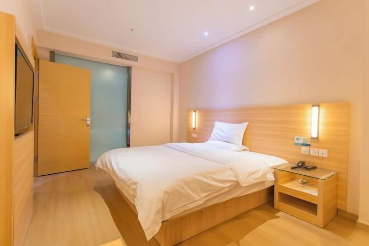 Une chambre d’hôtel avec un lit, une table de chevet et une porte.