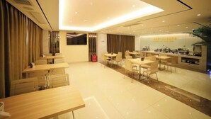 Un espace repas moderne avec plusieurs tables et chaises, un comptoir de cuisine et une grande fenêtre.