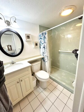 Un baño con inodoro, lavamanos, espejo y ducha.