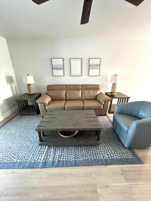 A living room with a sofa, a coffee table, a blue armchair, and two side tables with lamps. - Casa Mar - Unit 37 ; 2 Bedroom 2 Bath Beach Front (Siesta Key)