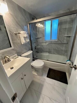 Ein Badezimmer mit Duschkabine, Toilette, Waschbecken und Spiegel.