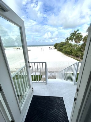 A beach view from a room with a white door and a black mat leading to a balcony. - Casa Mar - Unit 37 ; 2 Bedroom 2 Bath Beach Front (Siesta Key)