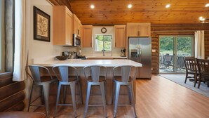 A kitchen with wooden cabinets, a stainless steel refrigerator, and a large island with bar stools.
