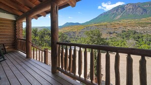 A wooden cabin with a balcony overlooking a mountainous landscape.