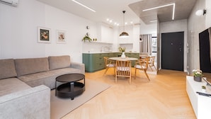 A modern living room with a sofa, a round coffee table, and a dining area with a table and chairs. - Doki Oliwkowy by Grand Apartments (Gdansk)