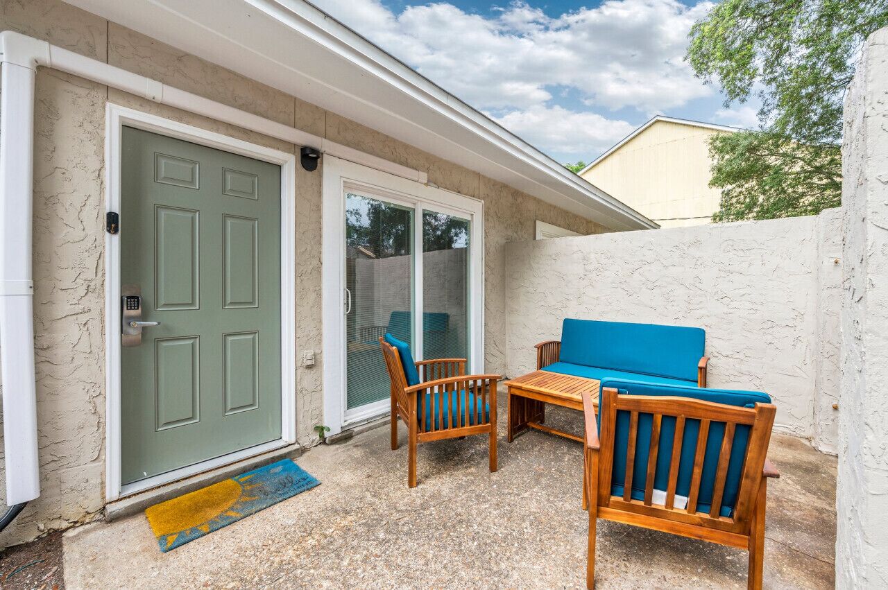 A patio with a sliding glass door, wooden furniture, and a doormat.