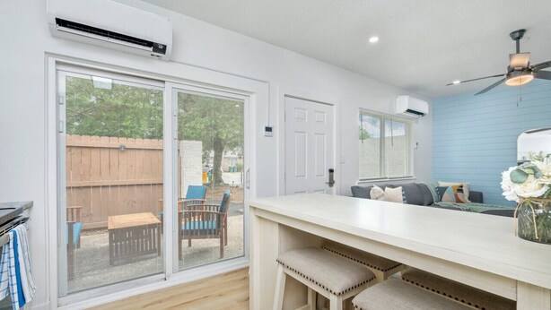 A kitchen with a sliding glass door leading to a patio, a ceiling fan, and a white countertop with stools.