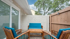 A wooden outdoor seating area with a table and chairs, a stone wall, and a wooden fence.