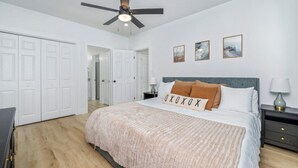 A bedroom with a bed, a ceiling fan, a nightstand, and a wardrobe.