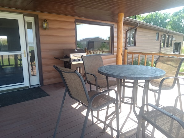 Eine überdachte Terrasse mit Grill, Sitzgelegenheit im Freien und Blick auf ein Haus.