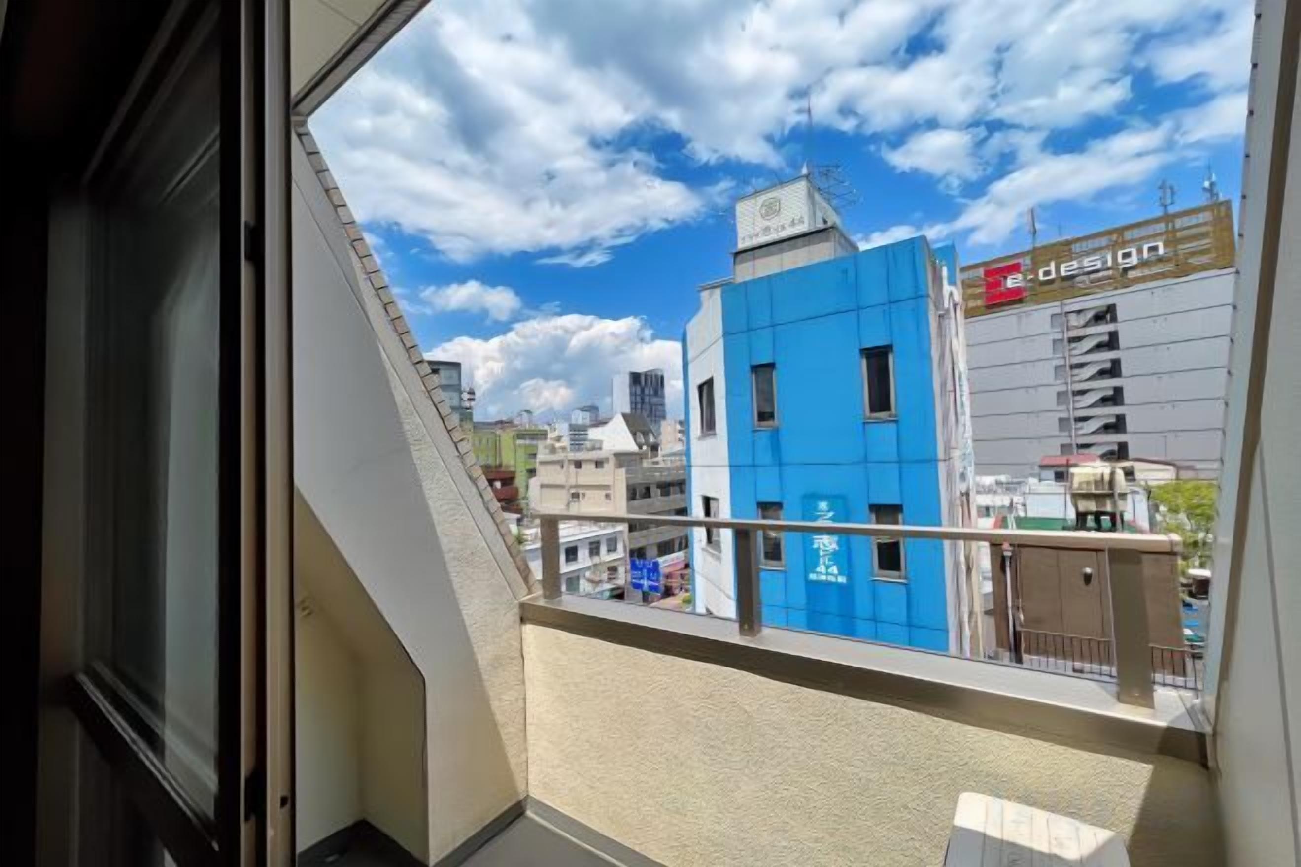A view from a balcony overlooking a cityscape with buildings, including a blue building with a sign that reads 'design.'