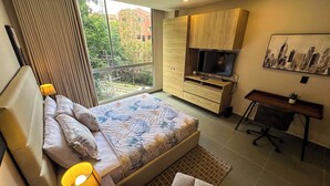 Un dormitorio moderno con una cama, un televisor y un escritorio.