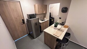 Cocina pequeña con refrigerador, lavamanos y un reloj en la pared.