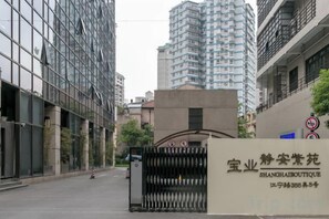 A modern building with a gated entrance, a signboard with text, and a clear sky. - Yupin Jing'an Ziyuan Apartment Hotel (Shanghai)