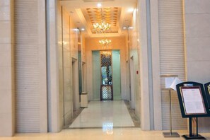 A hotel corridor with a chandelier, a reception desk, and a glass door. - Yupin Jing'an Ziyuan Apartment Hotel (Shanghai)