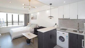 A modern hotel room with a bed, a small desk, a washing machine, and a kitchenette. - Yupin Jing'an Ziyuan Apartment Hotel (Shanghai)