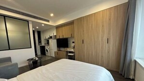 A modern hotel room with a large bed, a seating area, a kitchenette, and a TV. - Yupin Jing'an Ziyuan Apartment Hotel (Shanghai)