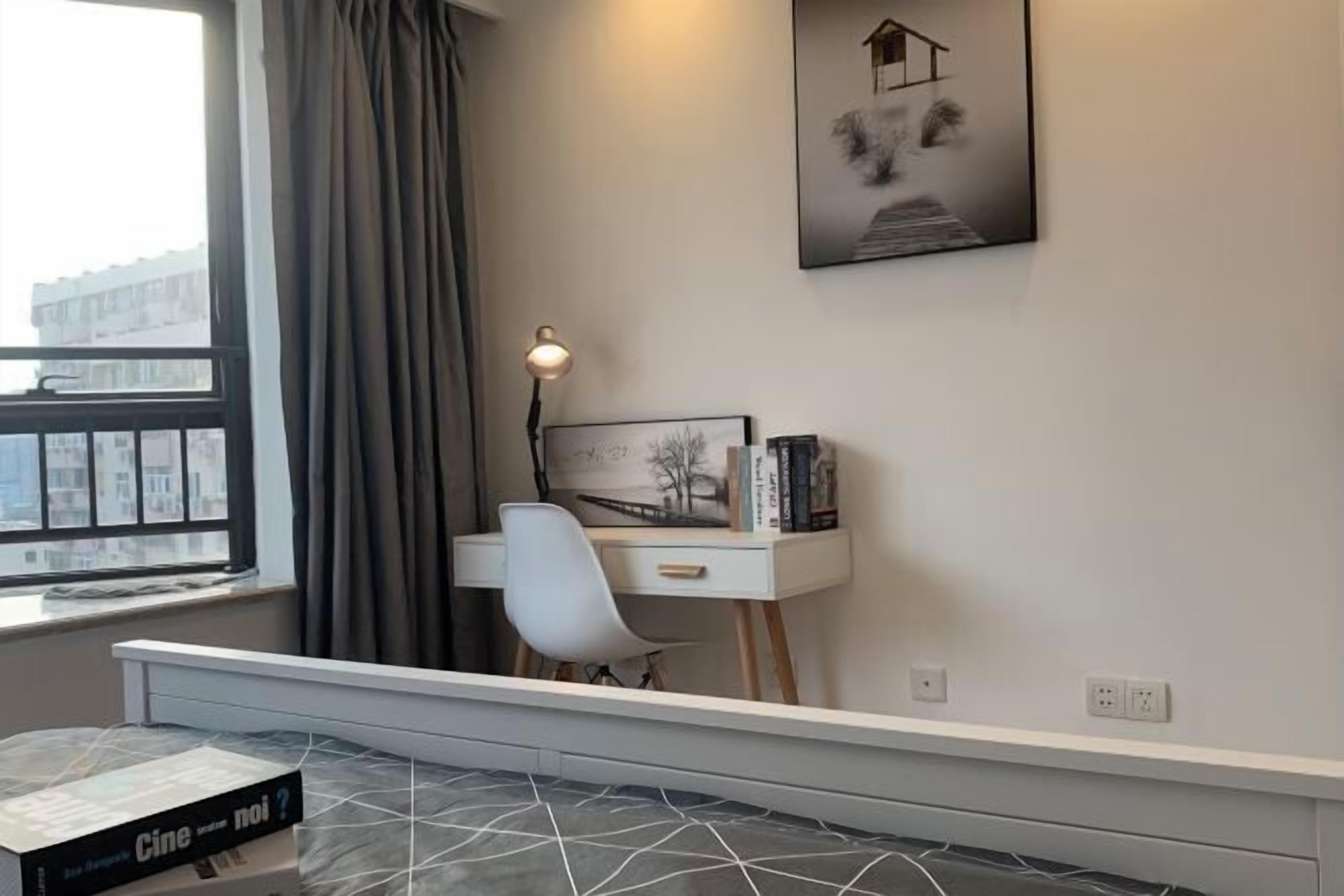 A room with a desk, chair, and a window with curtains.