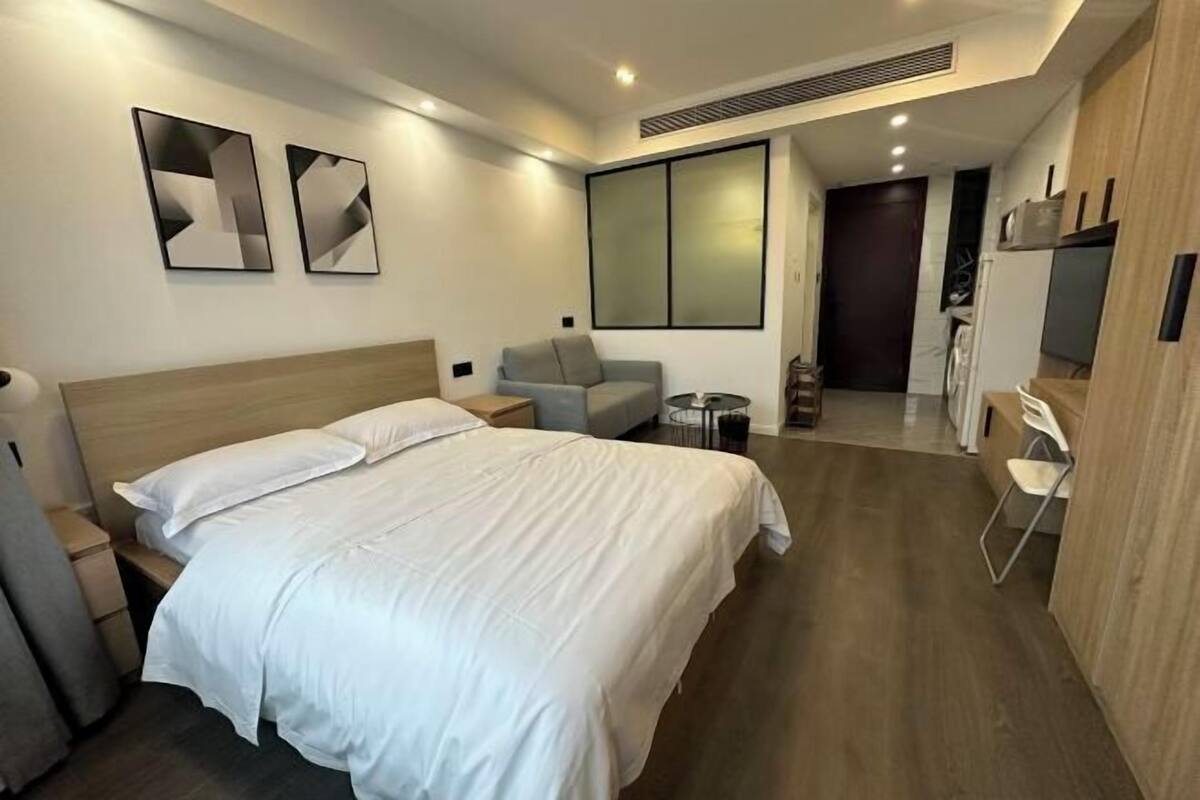 Ein modernes Hotelzimmer mit einem großen Bett, einem Schreibtisch, einem Sessel und einem Fernseher.