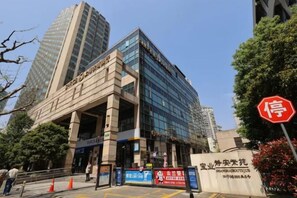 A modern building with a large entrance and signage indicating a business center. - Yupin Jing'an Ziyuan Apartment Hotel (Shanghai)