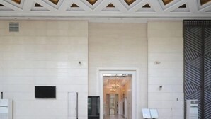 A modern interior with a central hallway leading to a reception area, featuring a geometric ceiling design and a patterned wall on the right. - Yupin Jing'an Ziyuan Apartment Hotel (Shanghai)