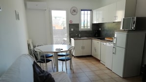 A compact kitchen with white cabinets, a microwave, and a coffee maker. There is a dining table with chairs and a sofa with pillows. - Clos des Plumbagos, between Avignon and the Ventoux (Monteux)