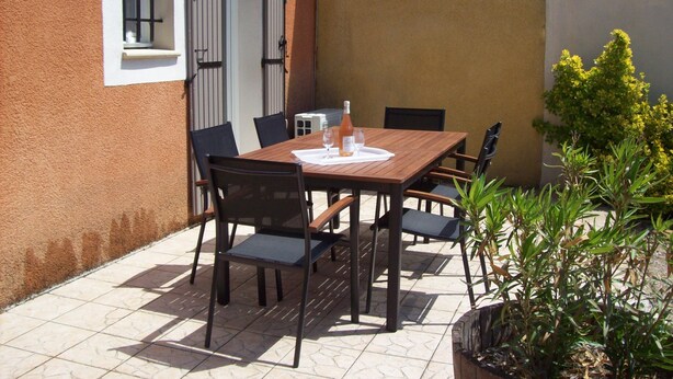 An outdoor patio with a wooden table and chairs, a bottle of wine, and a glass. - Clos des Plumbagos, between Avignon and the Ventoux (Monteux)