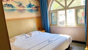 Ένα δωμάτιο ξενοδοχείου με ένα κρεβάτι, ένα παράθυρο με κουρτίνες και έναν τοίχο με έναν πίνακα.