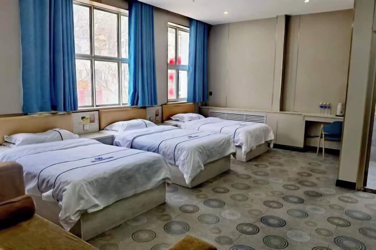 A hotel room with three beds, a desk, and a chair.