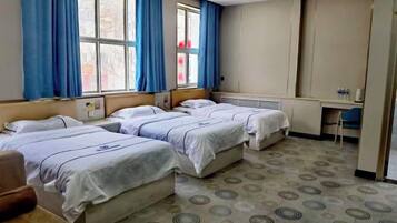 Une chambre d’hôtel avec trois lits, un bureau et une chaise.