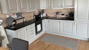 A modern kitchen with white cabinets, a black countertop, and a built-in oven. - Lovely and well equipped home with outdoor BBQ, ready for hiking in Seljestad. (Ullensvang)