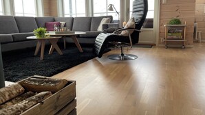 A modern living room with a grey sofa, a black leather chair, a small wooden table, and a black rug. - Lovely and well equipped home with outdoor BBQ, ready for hiking in Seljestad. (Ullensvang)