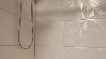 A bathroom with a bathtub, a showerhead, and a faucet.