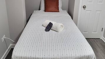 A bedroom with a bed, a pillow, a towel, and a door.