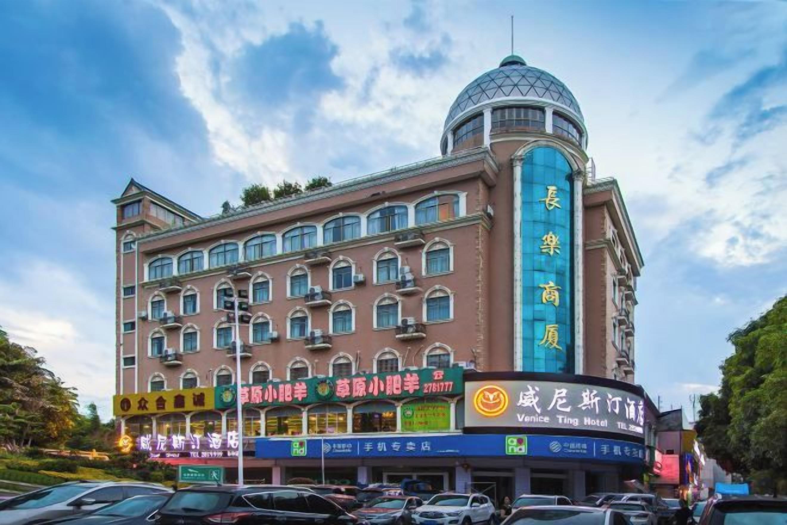 A multi-story hotel with a prominent dome on the top, multiple balconies, and a variety of signage indicating different services and amenities.